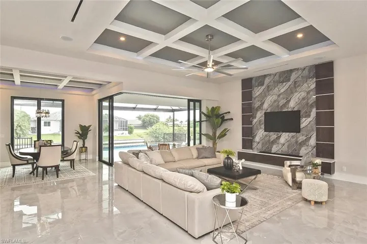 Living room featuring coffered ceiling, marble tiled floors, beamed ceiling, a ceiling fan, and a fireplace
