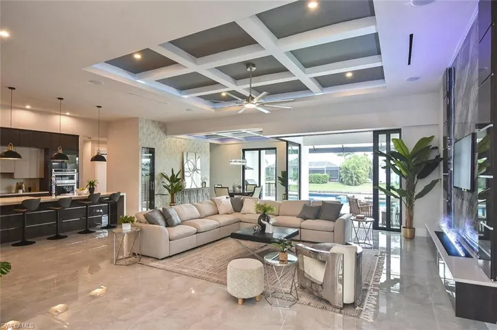Living room with coffered ceiling, light marble finish flooring, beam ceiling, a ceiling fan, and recessed lighting
