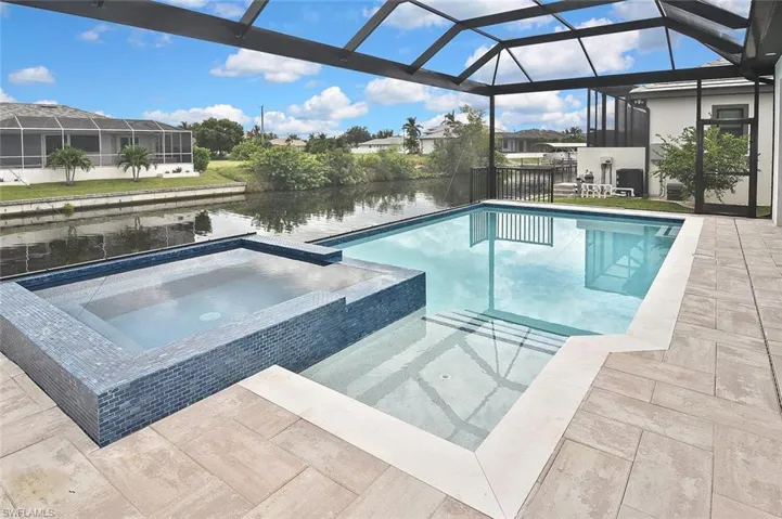 View of pool with a water view, a lanai, a pool with connected hot tub, a sunroom, and a patio