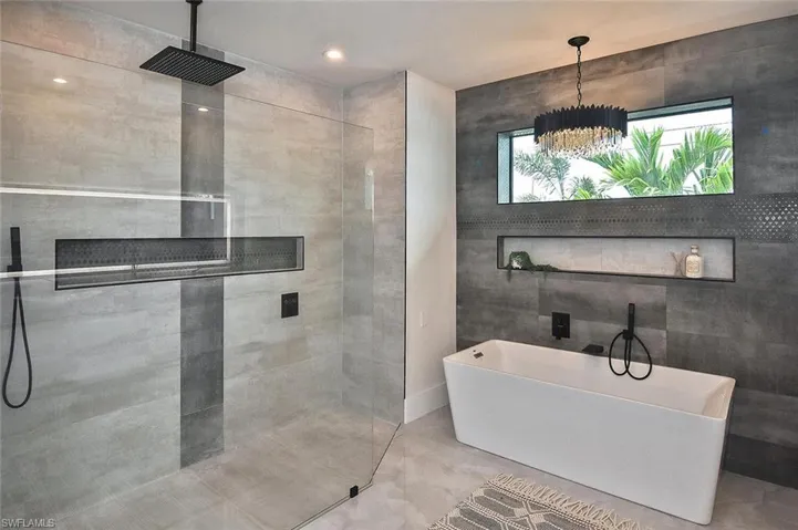 Bathroom with a freestanding tub, walk in shower, tile walls, and recessed lighting