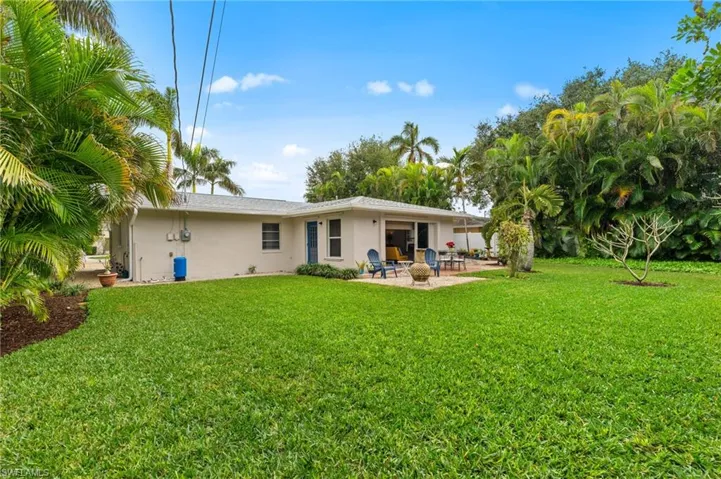 Rear view of property with a lawn and a patio