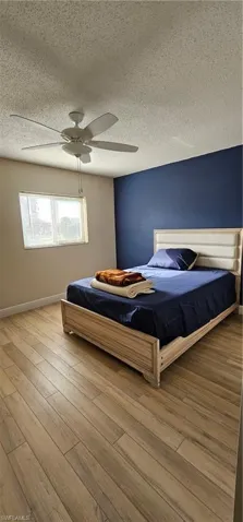 Unfurnished bedroom with a textured ceiling, light hardwood / wood-style floors, and ceiling fan