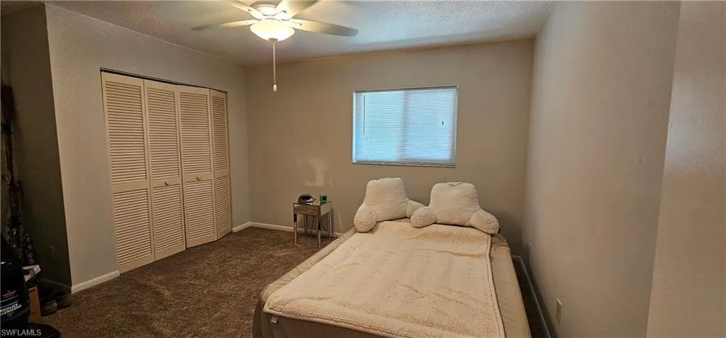Carpeted bedroom with ceiling fan and a closet