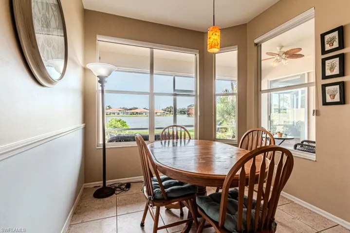 Dining area featuring ceiling fan, light tile patterned floors, a water view, and a wealth of natural light