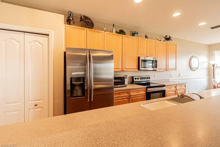 Kitchen with appliances with stainless steel finishes, light brown cabinets, and sink