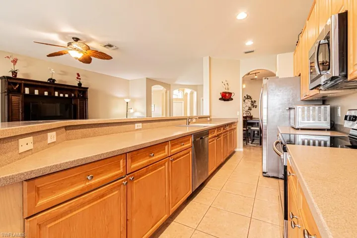 Kitchen with sink, ceiling fan, appliances with stainless steel finishes, and light tile patterned flooring