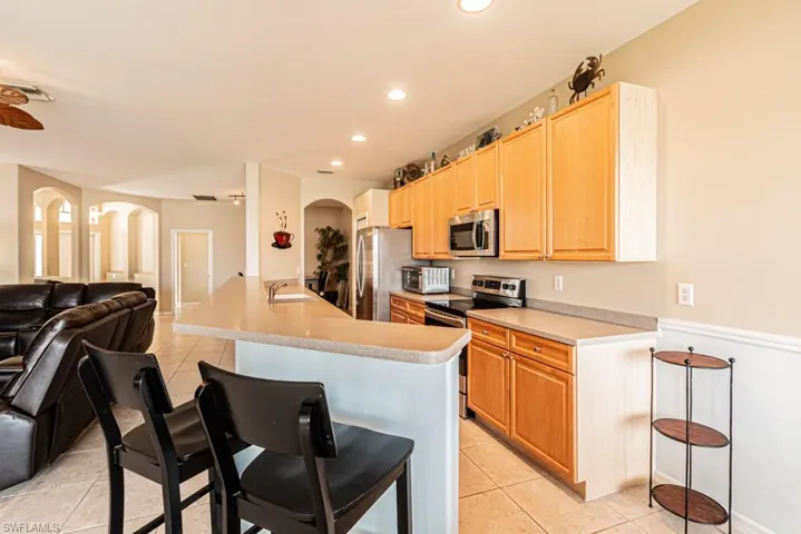 Kitchen with appliances with stainless steel finishes, sink, a kitchen breakfast bar, light tile patterned floors, and a kitchen island with sink