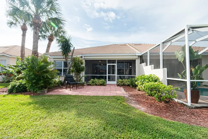 Back of property with a patio area, a lawn, and glass enclosure