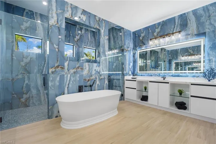 spa-like bathroom adorned in marbled tile, complete with dual vanities, an oversized shower, and a freestanding soaking tub.