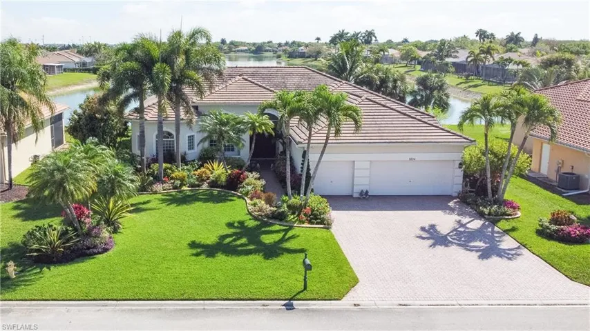Mediterranean / spanish house featuring an attached garage, a front yard, driveway, a tile roof, and stucco siding