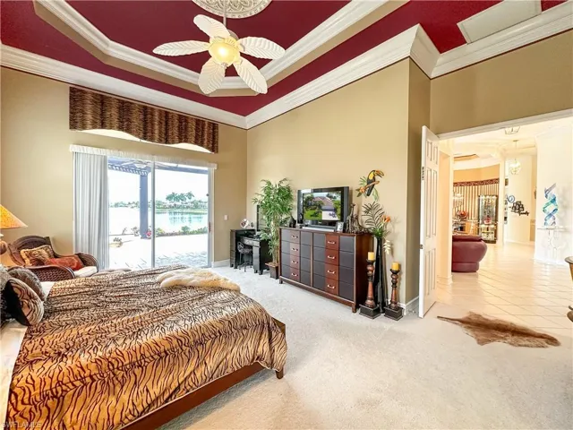 Bedroom featuring light colored carpet, access to outside, a high ceiling, crown molding, and a ceiling fan