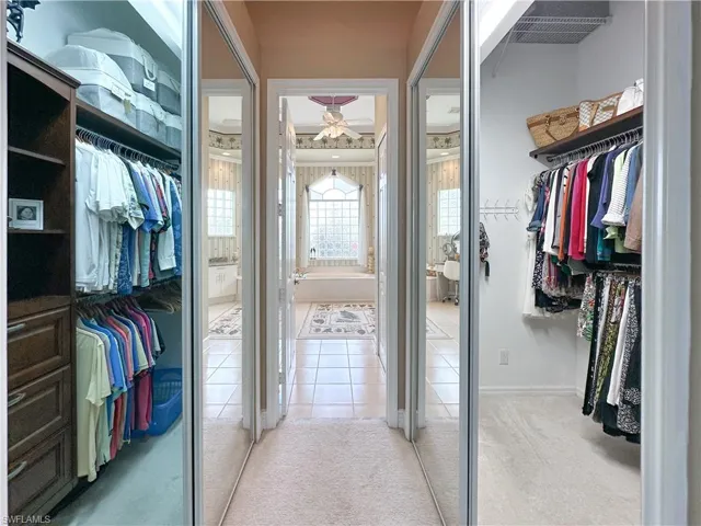 Walk in closet featuring light colored carpet, ceiling fan, and light tile patterned floors