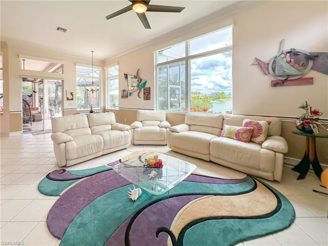 Living room featuring light tile patterned floors, hanging lights, plenty of natural light, and ornamental molding