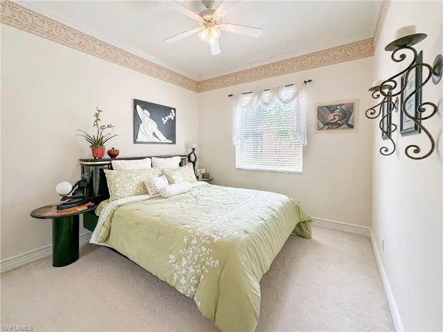 Carpeted bedroom with ornamental molding and a ceiling fan