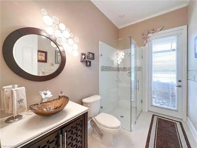 Full bathroom with vanity, a shower stall, light tile patterned floors, and crown molding