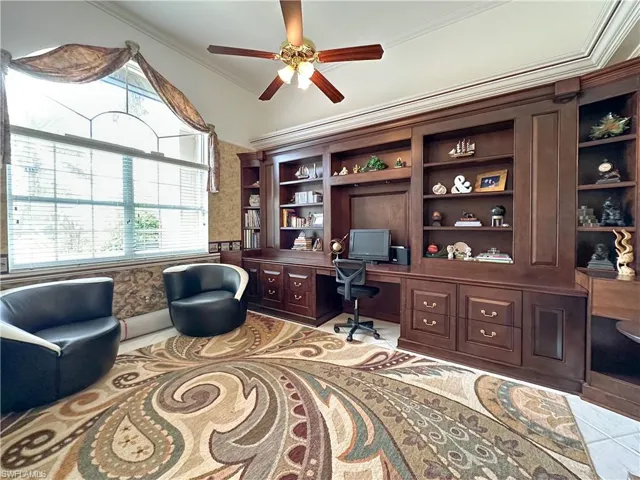 Office featuring built in desk, ornamental molding, ceiling fan, wallpapered walls, and a wainscoted wall