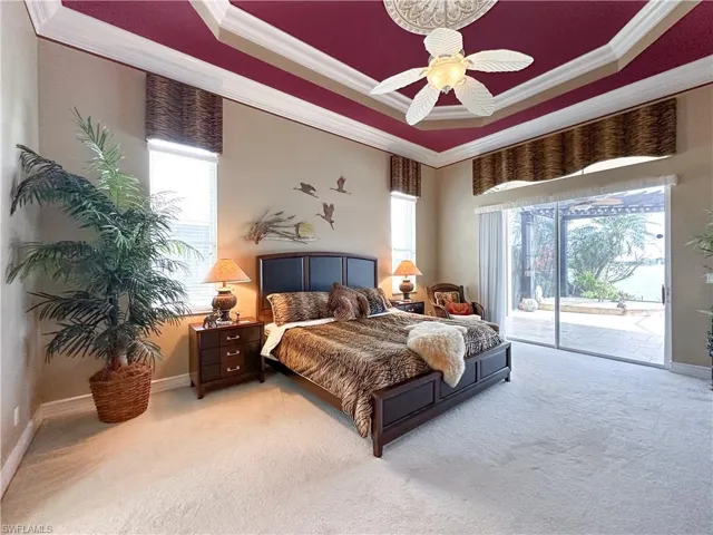Bedroom with crown molding, access to exterior, light colored carpet, ceiling fan, and a raised ceiling