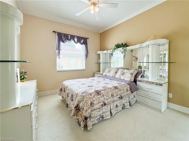 Bedroom featuring light colored carpet, ornamental molding, and ceiling fan