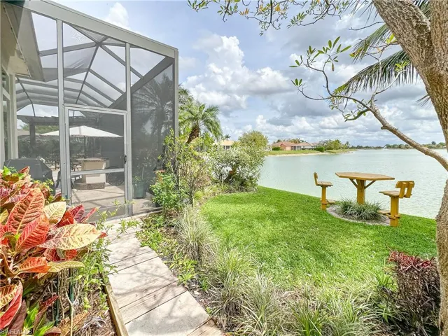 View of green lawn featuring a water view, a sunroom, and a lanai