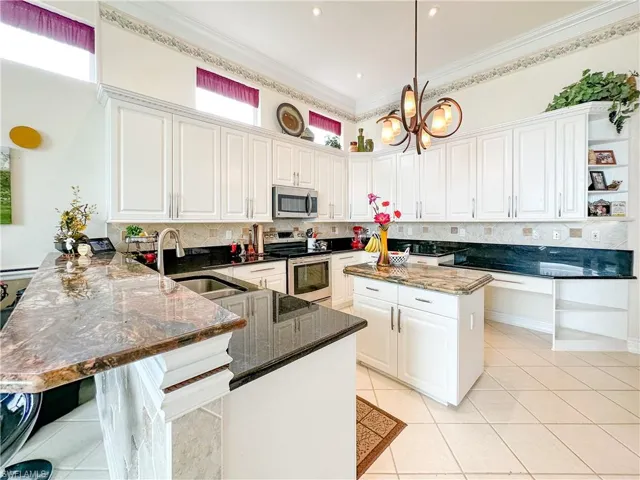 Kitchen featuring tasteful backsplash, a peninsula, white cabinetry, stainless steel appliances, and dark stone countertops