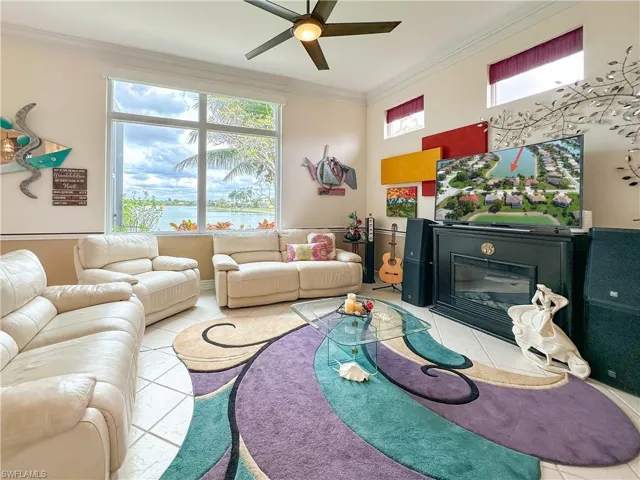 Living area with a glass covered fireplace, ceiling fan, crown molding, and tile patterned flooring