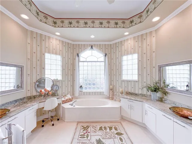 Full bath featuring vanity, a bath, and wallpapered walls