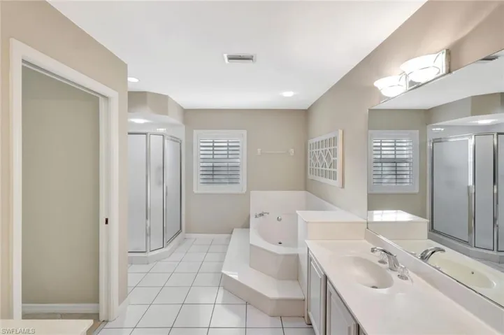 Full bath featuring vanity, a garden tub, a shower stall, and light tile patterned flooring