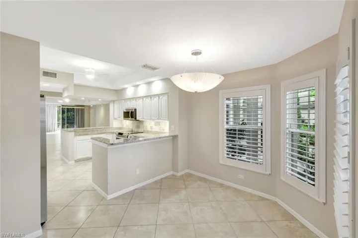 Kitchen with a peninsula, light stone counters, decorative backsplash, light tile patterned floors, and pendant lighting
