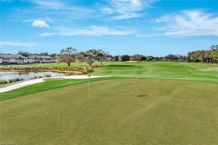 View of home's community with a water view, view of golf course, a yard, and a putting green