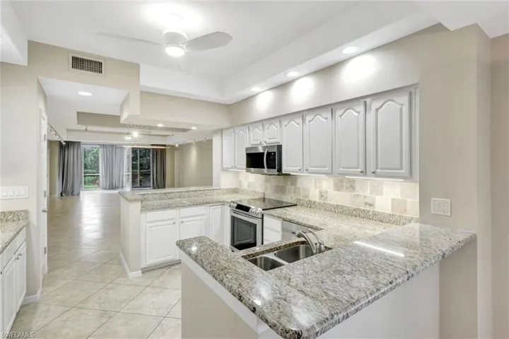 Kitchen with a peninsula, white cabinets, appliances with stainless steel finishes, decorative backsplash, and recessed lighting