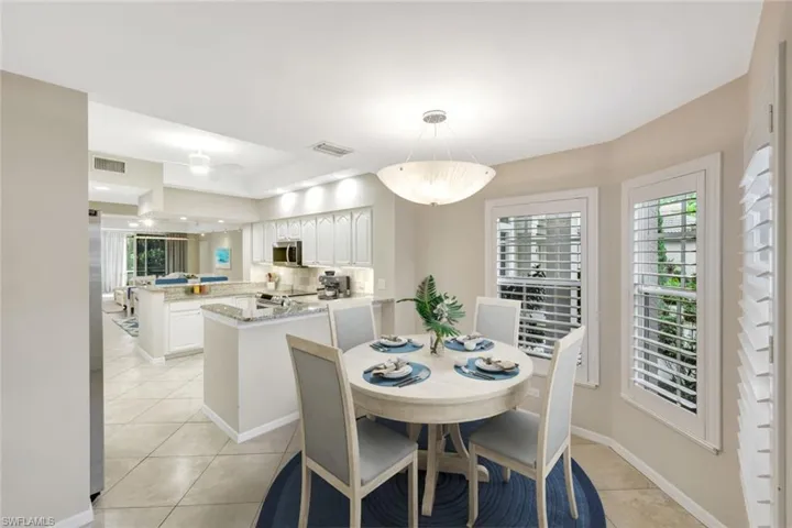 virtually staged Dining area with light tile patterned floors, healthy amount of natural light, and a tray ceiling