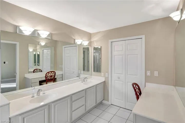 Full bathroom with double vanity, a closet, and light tile patterned flooring