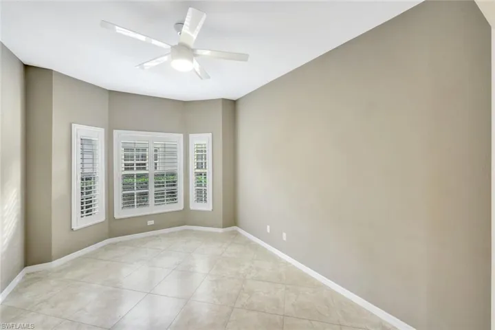 Empty room with a ceiling fan and light tile patterned floors