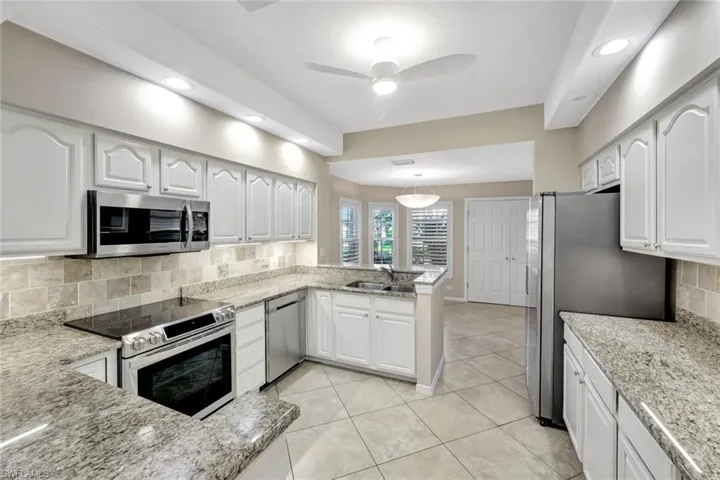Kitchen with backsplash, stainless steel appliances, white cabinets, and recessed lighting