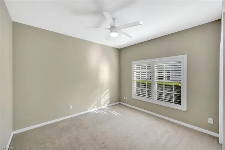 Carpeted empty room with baseboards and a ceiling fan