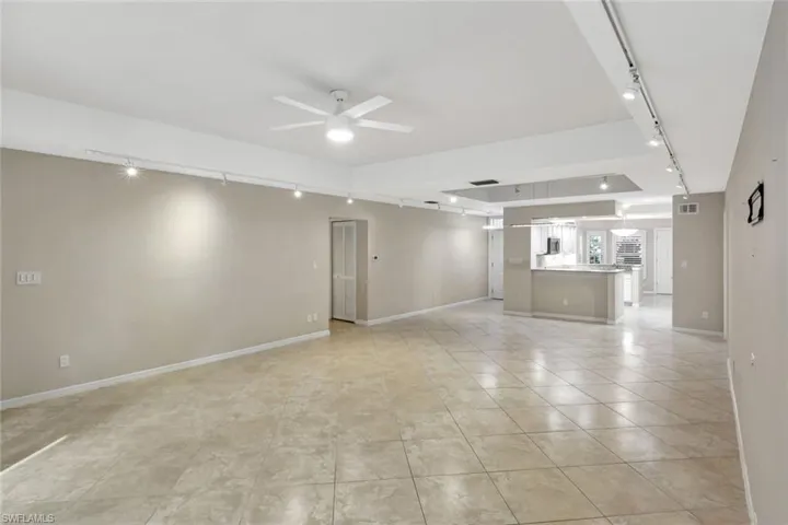 Unfurnished living room featuring track lighting, ceiling fan, and light tile patterned floors