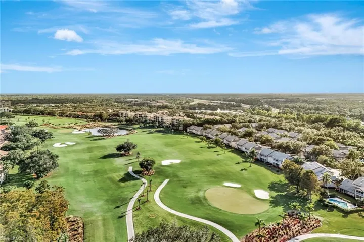 Aerial perspective of suburban area featuring a golf club and a nearby body of water