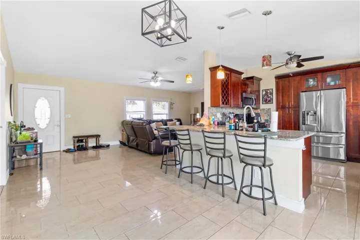 Kitchen featuring tasteful backsplash, a breakfast bar, a peninsula, a ceiling fan, and stainless steel appliances