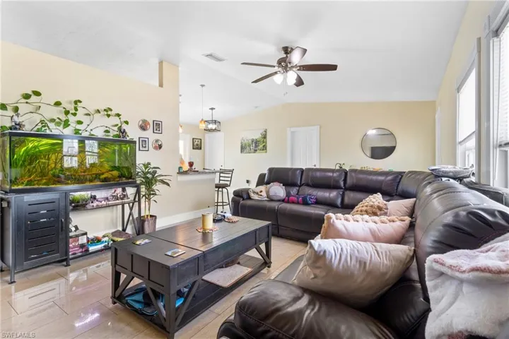 Living room with visible vents, a ceiling fan, and vaulted ceiling