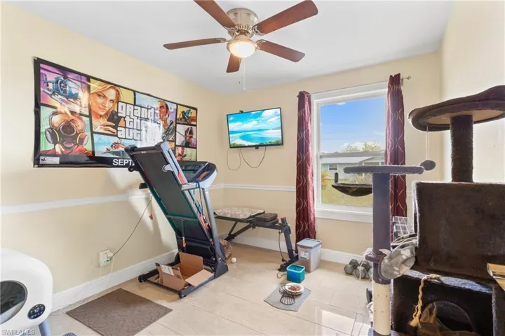 Exercise area featuring ceiling fan, tile patterned flooring, and baseboards