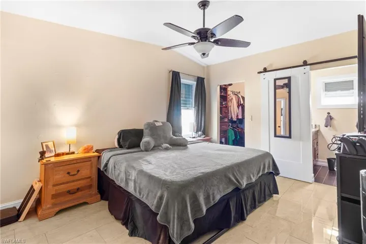 Bedroom with a closet, baseboards, a barn door, a walk in closet, and lofted ceiling