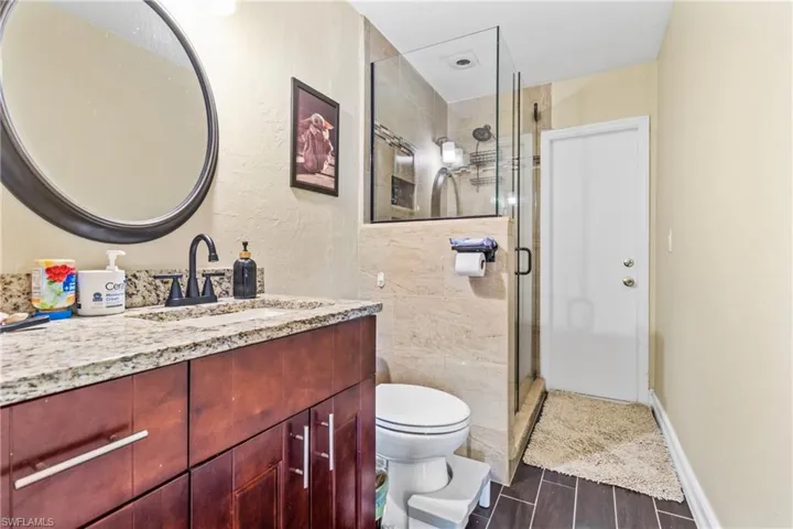 Full bath with toilet, vanity, a shower stall, and wood finish floors