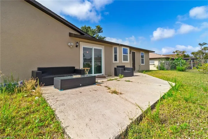 Back of house featuring a patio, stucco siding, fence, and a yard