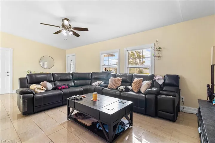 Living room featuring baseboards, light tile patterned flooring, and ceiling fan