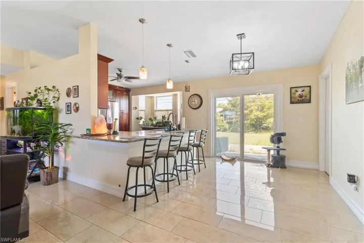 Kitchen featuring a peninsula, visible vents, decorative light fixtures, a breakfast bar area, and baseboards