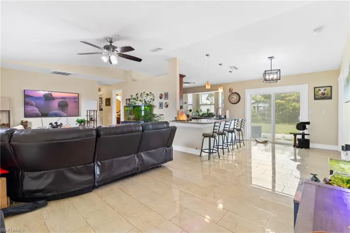 Living room with baseboards, a ceiling fan, and visible vents