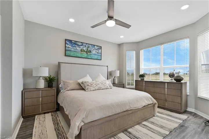 Bedroom with wood finished floors, multiple windows, a ceiling fan, and recessed lighting