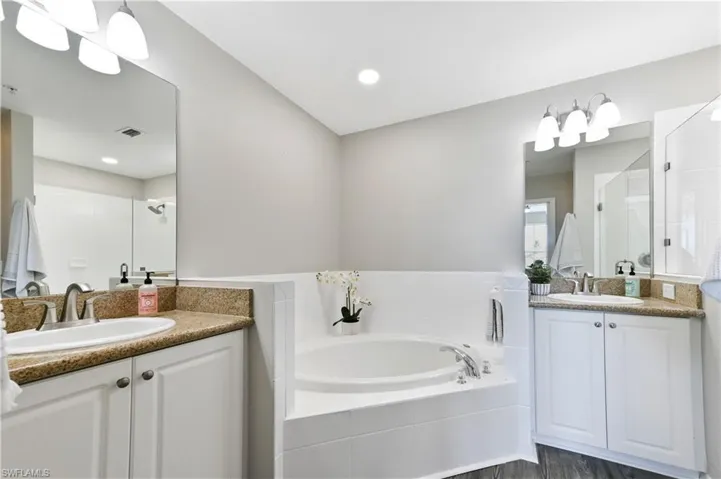 Full bath with two vanities, a garden tub, and a stall shower