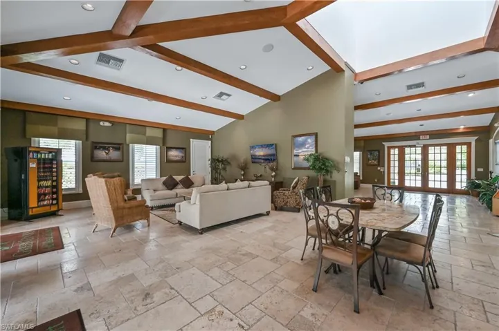 Dining room featuring stone tile flooring, healthy amount of natural light, beam ceiling, and high vaulted ceiling