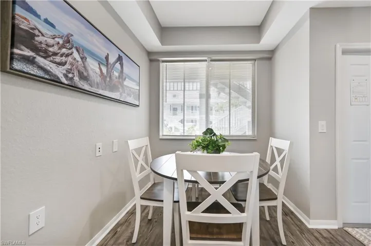 Dining space featuring dark wood-style flooring and a raised ceiling